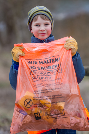 Kind mit Müllsack beim Sammeln